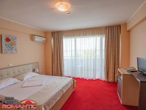 um quarto de hotel com uma cama e uma televisão em Hotel Romantic em Mamaia