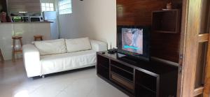 a living room with a white couch and a flat screen tv at Casa dos Coqueiros Praia de Camburi, condomínio in Camburi