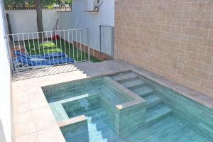 una piscina frente a una pared de ladrillos en Bungalow La Roa II, en Conil de la Frontera