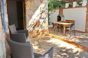a patio with chairs and a table and a fireplace at Bungalow La Roa II in Conil de la Frontera