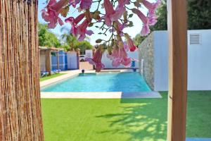 Una vista de una piscina con flores rosas. en Bungalow La Roa II, en Conil de la Frontera