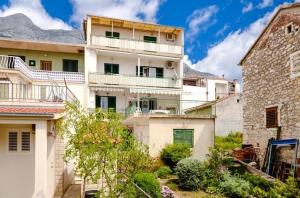 a large white building with mountains in the background at Apartman Dvor in Makarska