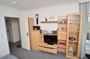 een woonkamer met een tv en een boekenplank bij Appartement-254 in Westerland