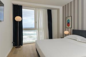 a bedroom with a bed and a large window at Hotel Punta Tipa in Trapani