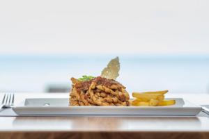 a plate of food on a table with fries at Hotel Punta Tipa in Trapani