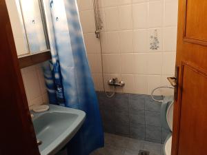 a bathroom with a blue shower curtain and a sink at House Kosmas on the beach in Sarti
