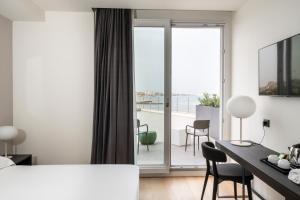 a hotel room with a bed and a desk and a balcony at Hotel Punta Tipa in Trapani
