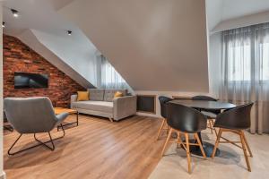 - un salon avec une table, des chaises et un canapé dans l'établissement Apartmani Studio Proforma, à Kolašin