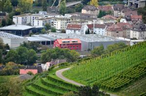 a town with a red building on a hill with vineyards at Gästehaus abz Stuttgart in Stuttgart