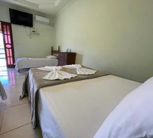 a room with two beds and a tv on the wall at Tijota Hotel Fazenda in Ipatinga