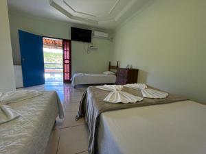 a room with two beds and a tv on the wall at Tijota Hotel Fazenda in Ipatinga