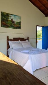 a bedroom with a large bed with white sheets at Tijota Hotel Fazenda in Ipatinga