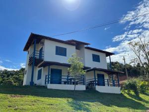 a white house with blue windows on a green field at Tijota Hotel Fazenda in Ipatinga