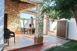 un patio con una mesa y una pared de piedra en Chalet La Roa III, en Conil de la Frontera