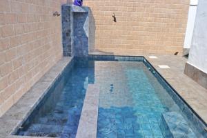 a swimming pool with a waterfall in a brick wall at Chalet La Roa III in Conil de la Frontera