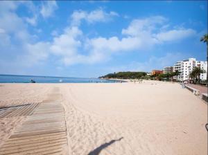 a sandy beach with a wooden boardwalk and the ocean at SeaHomes Vacations, FENALS BEACH&CHIC, pk, top apartment full equipped in Lloret de Mar
