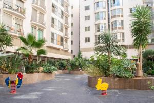 un edificio con palmeras y juguetes en un patio en New Estrelitzia Luxury Apartamen, en Santa Cruz de Tenerife