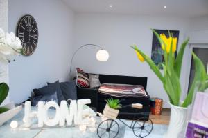 a living room with a black couch and a clock at Gästewohnung Mönchengladbach Rheindahlen in Mönchengladbach