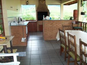 a kitchen with a counter and a table and chairs at Chacara na Serra da Mantiqueira in Santo Antônio do Pinhal