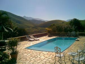 a swimming pool with chairs and a view of mountains at Chacara na Serra da Mantiqueira in Santo Antônio do Pinhal