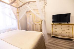 - une chambre avec un lit et une commode avec une télévision dans l'établissement Chambre a Baldaquin Maison de L'Église Du couvent, à Narbonne