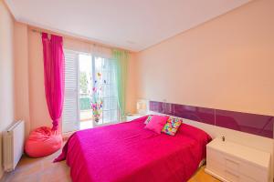a bedroom with a pink bed and a window at Bungalow Azalea - PlusHolidays in Calpe