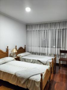 a hotel room with two beds and two lamps at Baires Portomarin in Portomarin