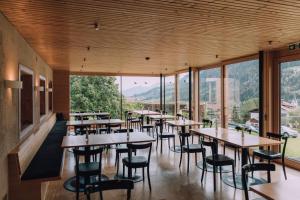 ein Restaurant mit Tischen und Stühlen und großen Fenstern in der Unterkunft Naturhotel Chesa Valisa in Hirschegg