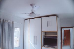 a kitchen with white cabinets and a ceiling fan at 100 metros da praia das Castanheiras,com garagem, internet, cadeiras de praia, cooler,roupas de cama e banho in Guarapari