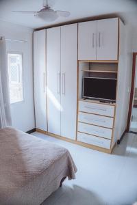 um quarto com uma cama e um armário com um micro-ondas em 100 metros da praia das Castanheiras,com garagem, internet, cadeiras de praia, cooler,roupas de cama e banho em Guarapari