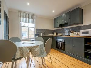 a kitchen with green cabinets and a table and chairs at Pass the Keys The Rafters - Impressive High Street Apartment in Whitstable