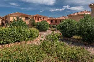 a row of houses in a yard with bushes at Baia de Bahas Residence in Golfo Aranci