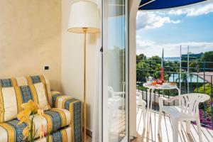 a living room with a couch and a balcony with a table at Sant Alphio Garden Hotel & SPA in Giardini Naxos