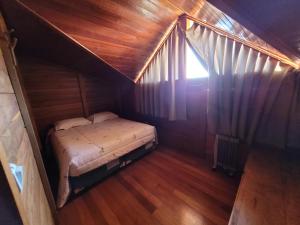 um pequeno quarto com uma cama numa casa de madeira em Hotel Fazenda Boutique Terra do Gelo em Bom Jardim da Serra