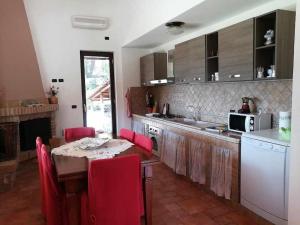 a kitchen with a table and red chairs in it at VILLA CYCAS relax tra mare e natura in Sperlonga