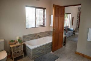 a bathroom with a bath tub and a toilet at Sol Montis Guest Cottage in Paarl