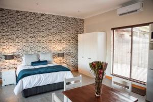 Un dormitorio con una cama y una mesa con un jarrón de flores en Sol Montis Guest Cottage, en Paarl