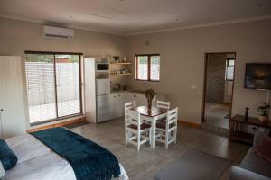 a bedroom with a bed and a table and a kitchen at Sol Montis Guest Cottage in Paarl +7 photos