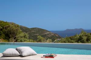 Fternón的住宿－High-end Villa Faos "One"，两个枕头和一个书坐在游泳池旁边的桌子上