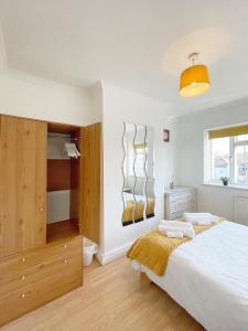 1 dormitorio con 1 cama blanca grande y armarios de madera en 3 bed duplex flat, free WIFI & Netflix, Ideal for contractors, en Gravesend