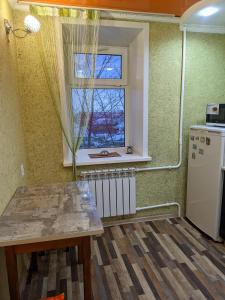 eine Küche mit einem Tisch und einem Fenster in der Unterkunft Квартира в районе жд вокзала in Schtschutschinsk