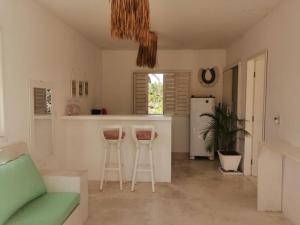 uma cozinha e sala de estar com um sofá e bancos em La Mangrove - Casa com piscina na Praia do Preá em Prea