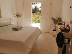 a bedroom with a bed and a door with a window at La Mangrove - Casa com piscina na Praia do Preá in Prea