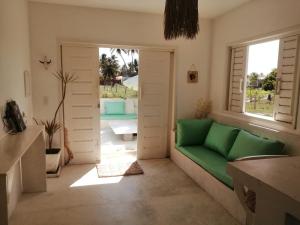 a living room with a green couch and a window at La Mangrove - Casa com piscina na Praia do Preá in Prea