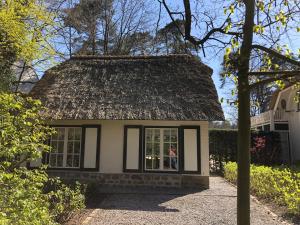 uma pequena casa com telhado de palha em Schilde Cottage em Schilde