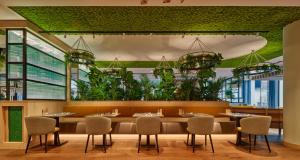 ein Restaurant mit einem großen Tisch mit Stühlen und Pflanzen in der Unterkunft voco The Hague, an IHG Hotel in Den Haag