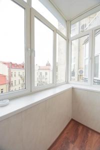 Habitación blanca grande con ventanas y suelo de madera. en Comfortable Apartment on Mikhaylovskiy lane, en Kiev