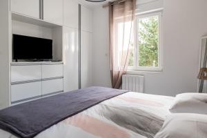 a white bedroom with a bed and a television at Salicorne in Frehel