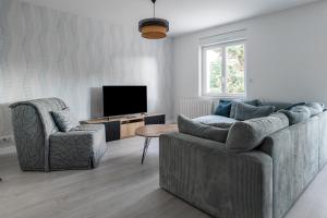 a living room with a couch and two chairs and a television at Salicorne in Frehel