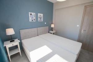 sypialnia z białym łóżkiem i niebieską ścianą w obiekcie Infinity Appartments w mieście Ajia Paraskiewi